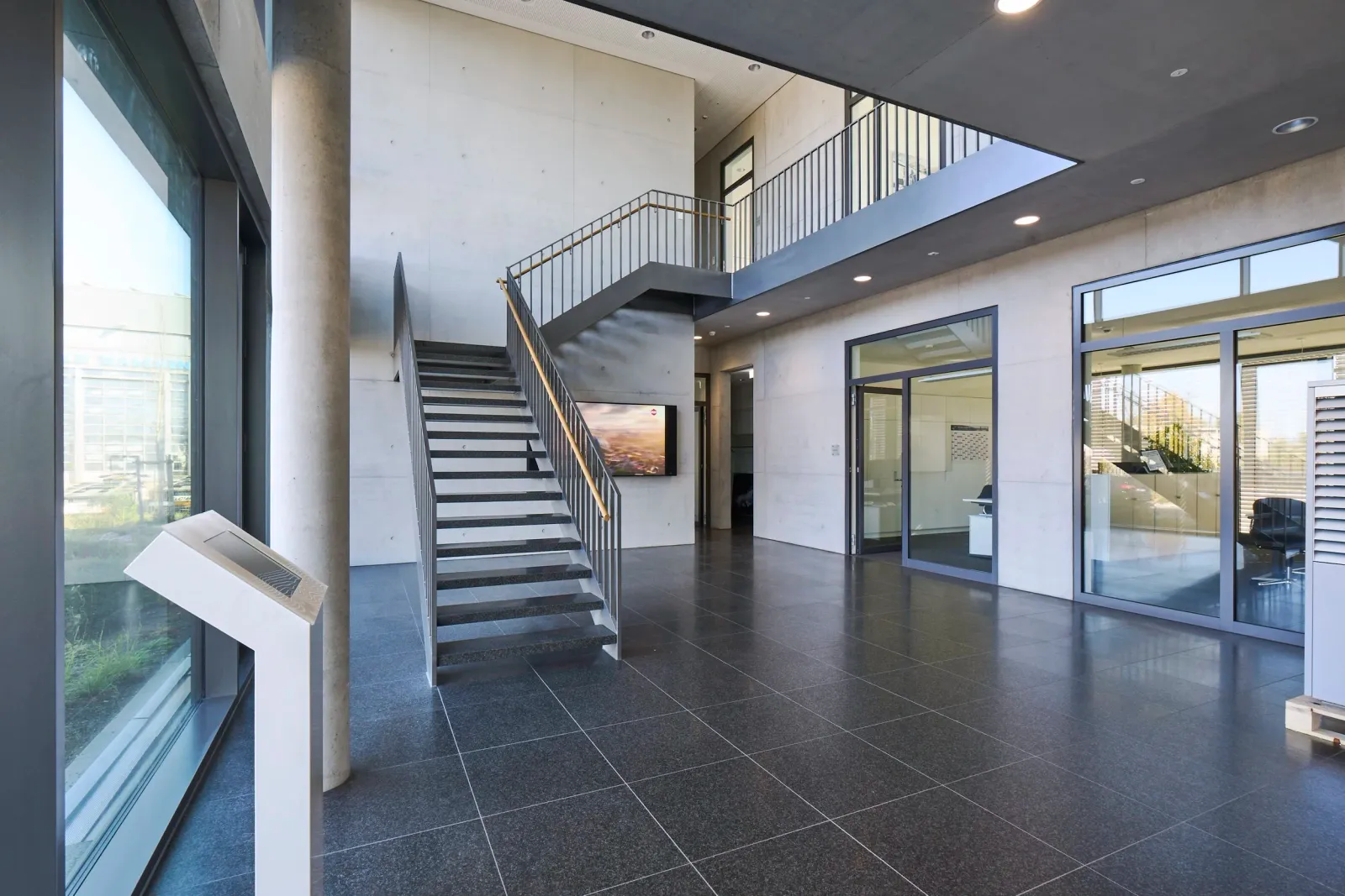 Foyer mit Treppe, Sichtbeton und Blick in die Büroräume