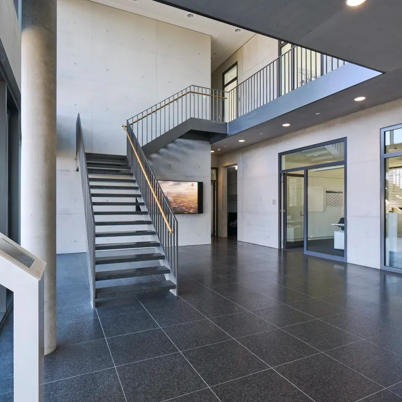 Foyer mit Treppe, Sichtbeton und Blick in die Büroräume