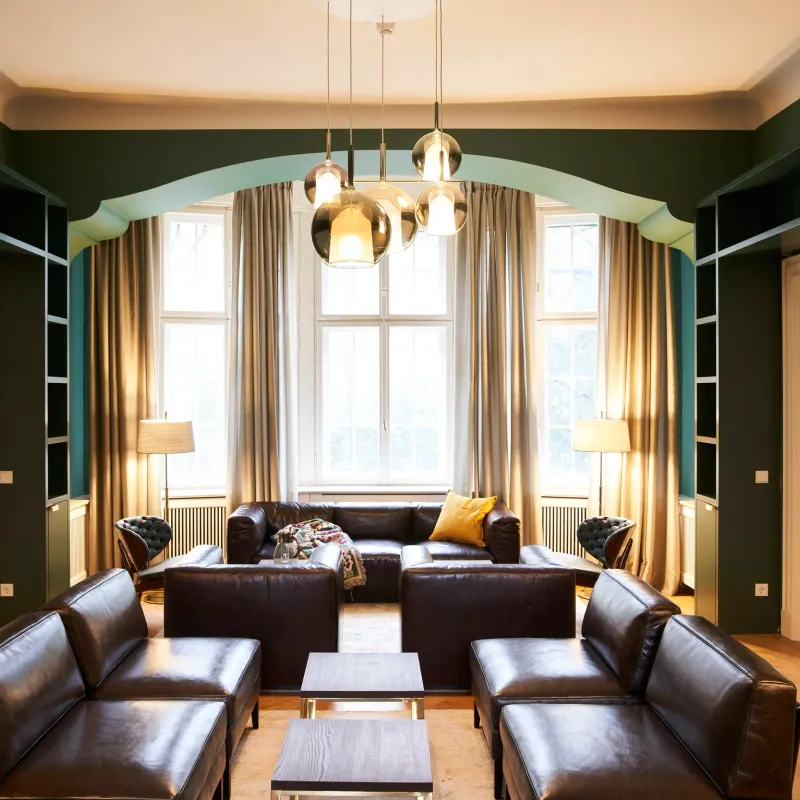 Symmetrischer Blick durch die Flügeltür in den grünen Salon mit Ledersofas