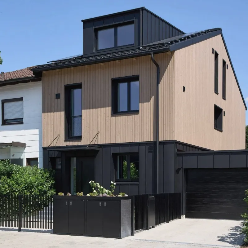 Straßenansicht mit Holzfassade, schwarzer Blechverkleidung und Garage