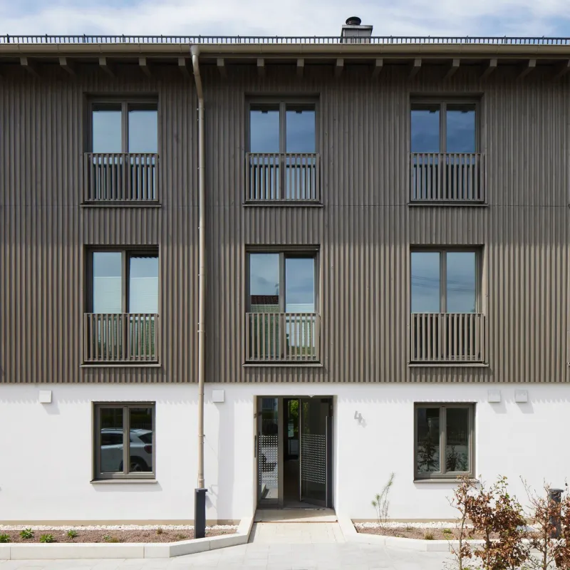 Straßenansicht mit Holzlamellenfassade und Balkonen