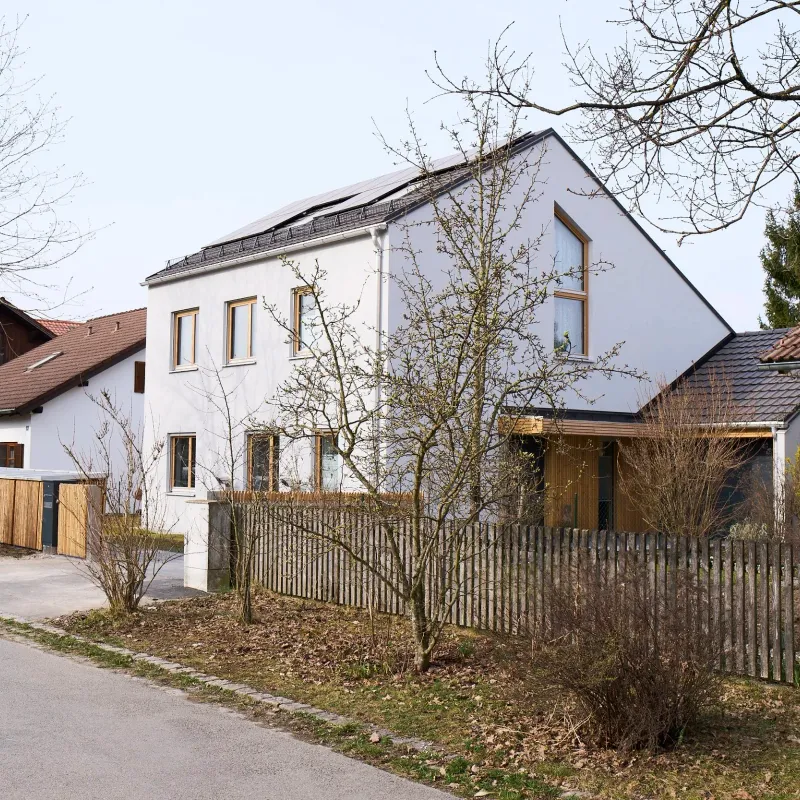 Straßenansicht mit Satteldach, Photovoltaikanlage und Holzlattenzaun