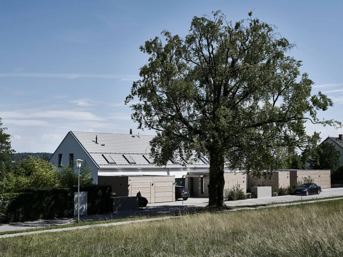 Reihenhauszeile mit Holzfassade vor altem Baumbestand