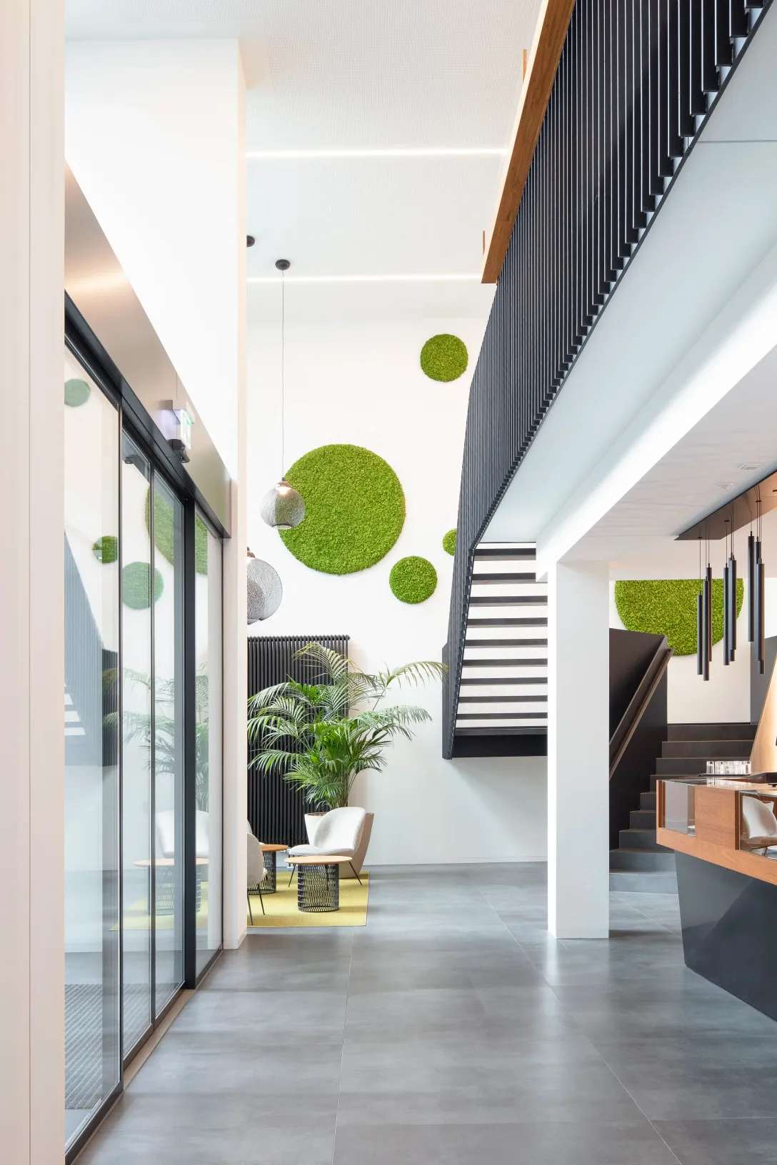 Lobby mit offener Treppe und Moosbildern an der Wand