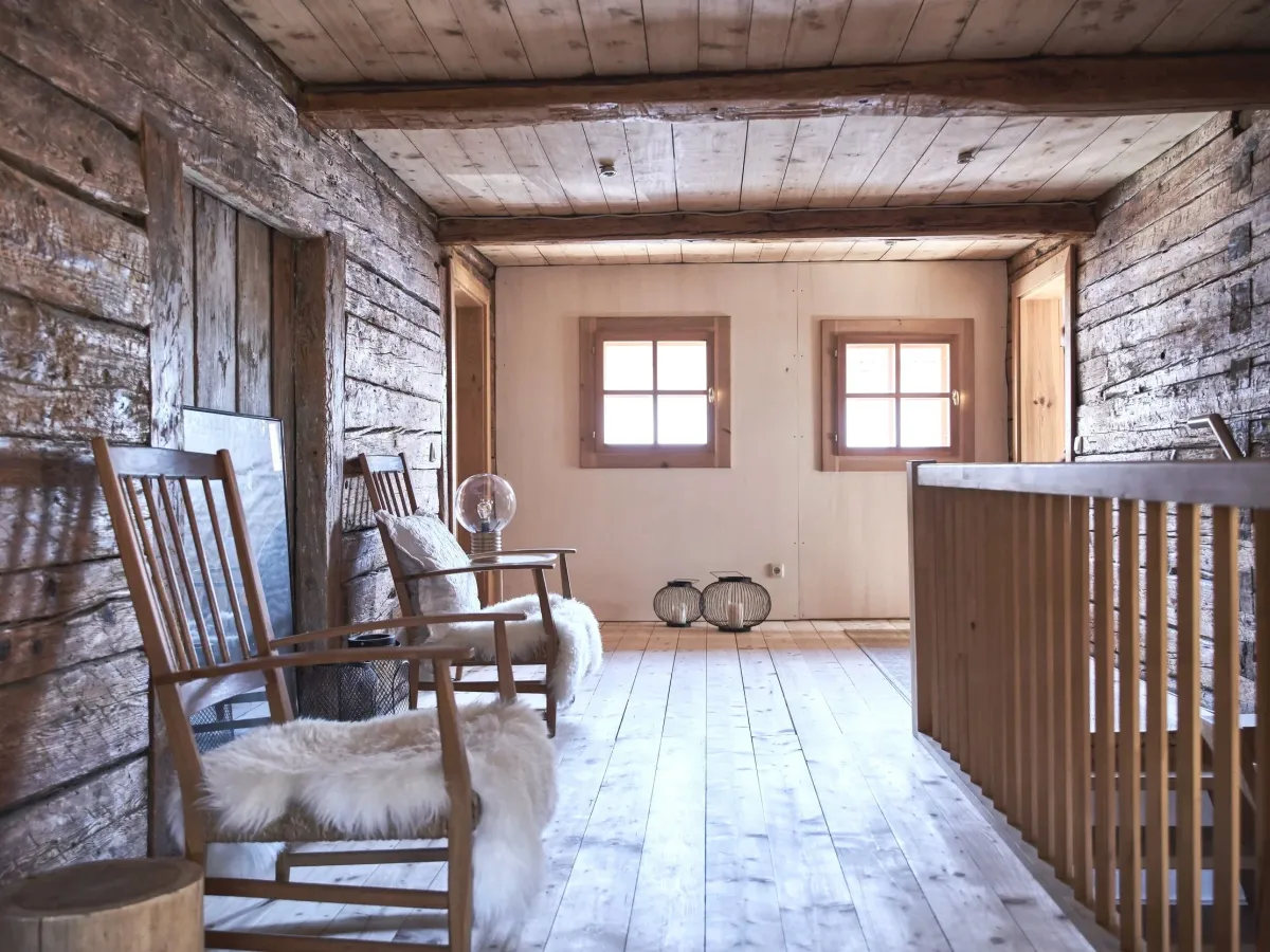 Galerie mit historischem Blockholz, Schaukelstühlen und Schaffellen