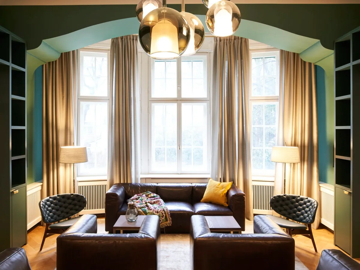 Sitzgruppe mit Ledersofas unter goldenen Kugelleuchten