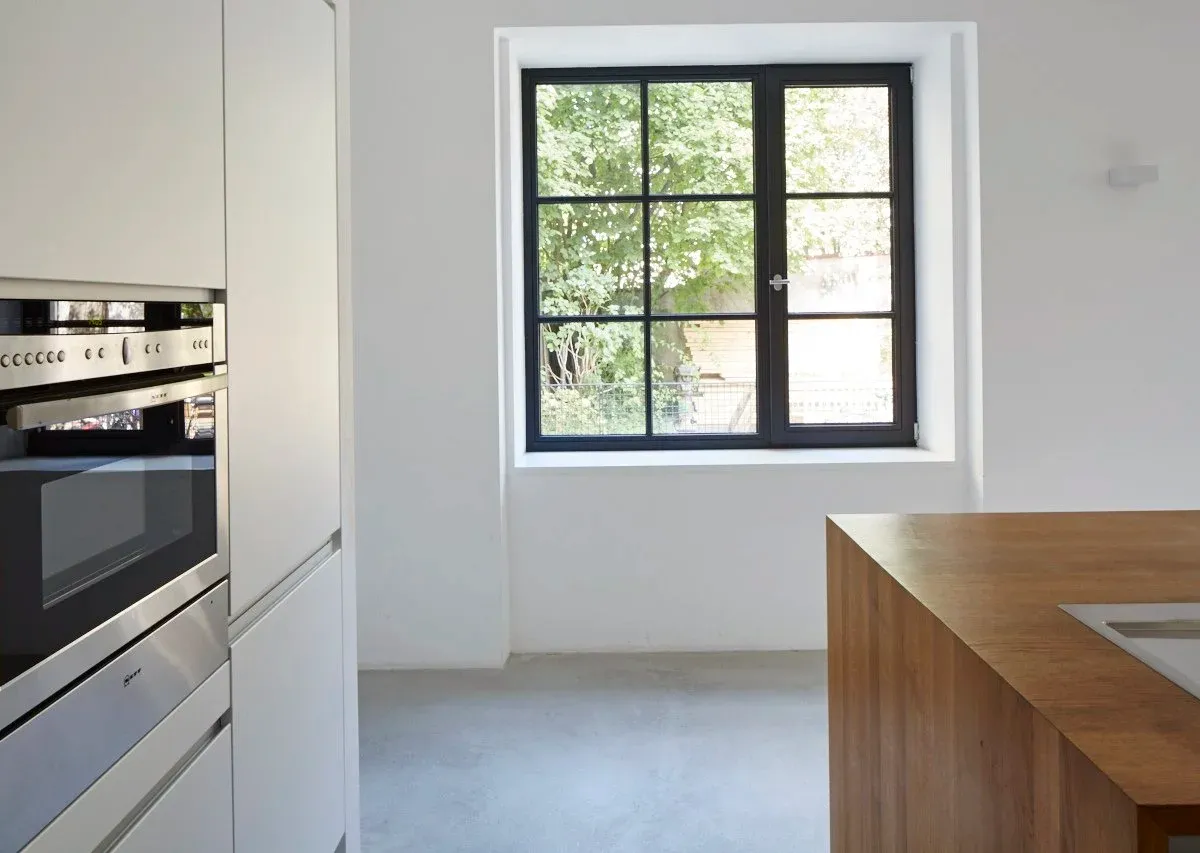 Küche mit Einbaubackofen und Sprossenfenster zum Garten