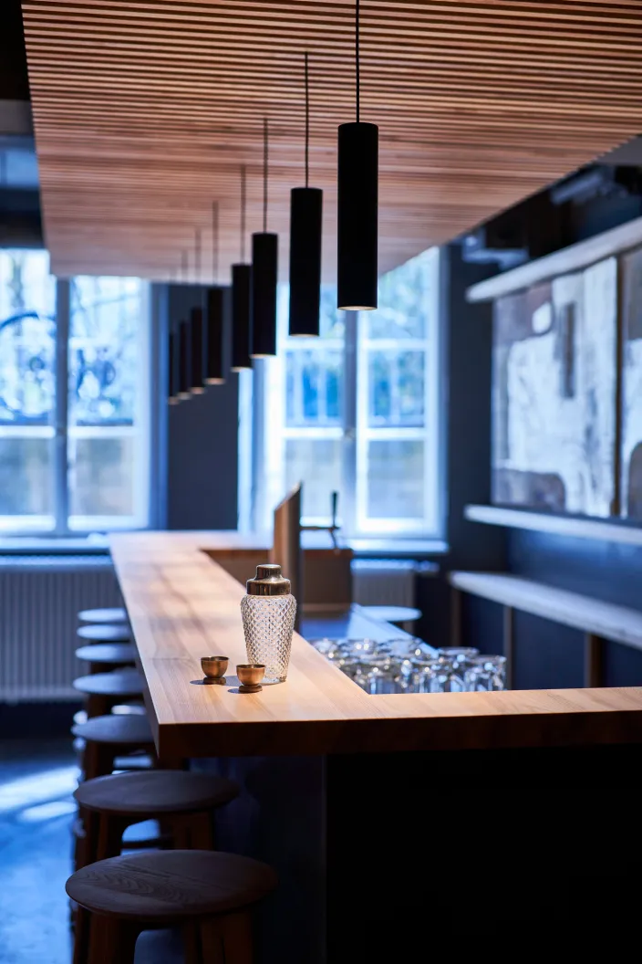 Theke mit Pendelleuchtenreihe und Hockern