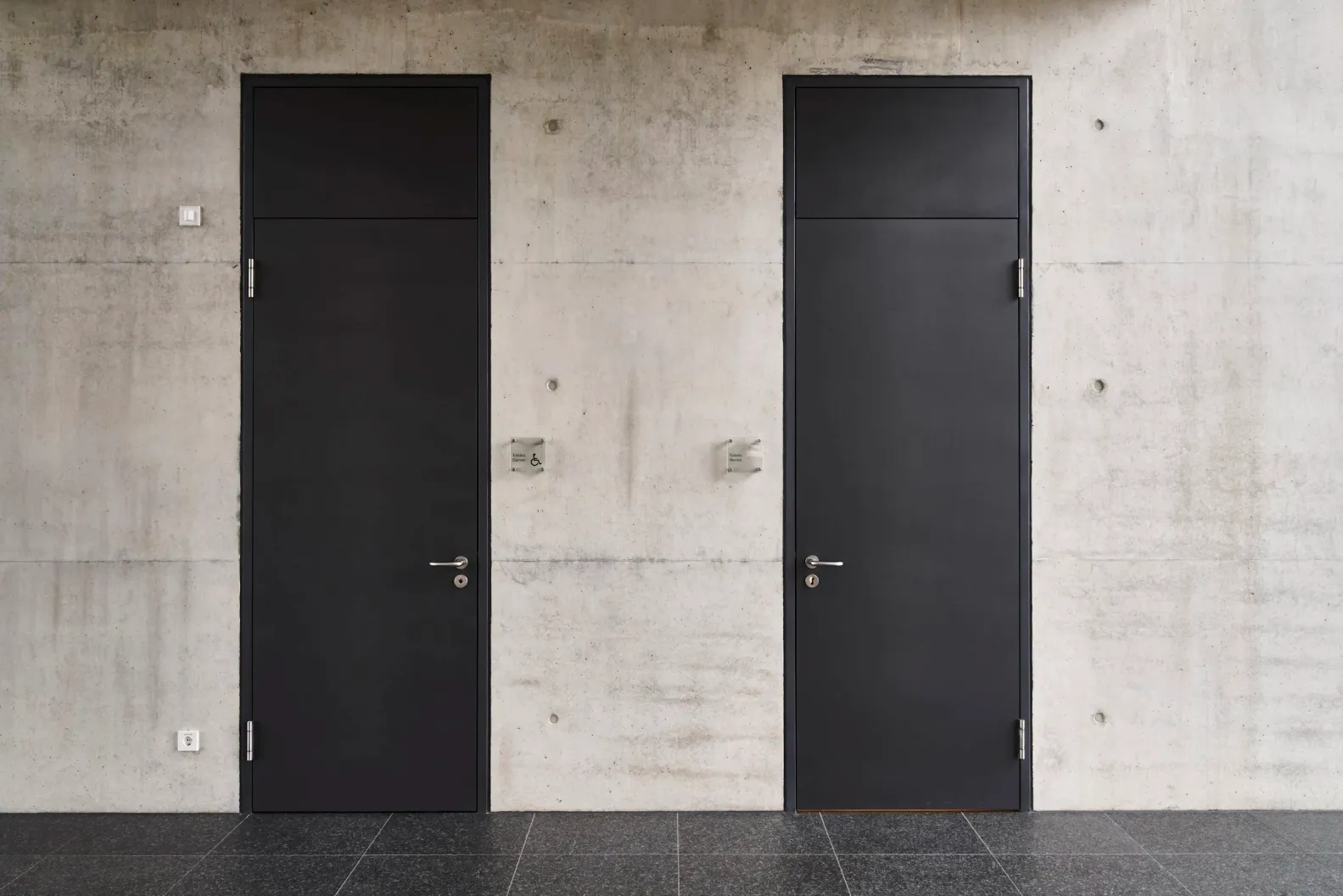 WC-Türen aus Metall vor Sichtbetonwand