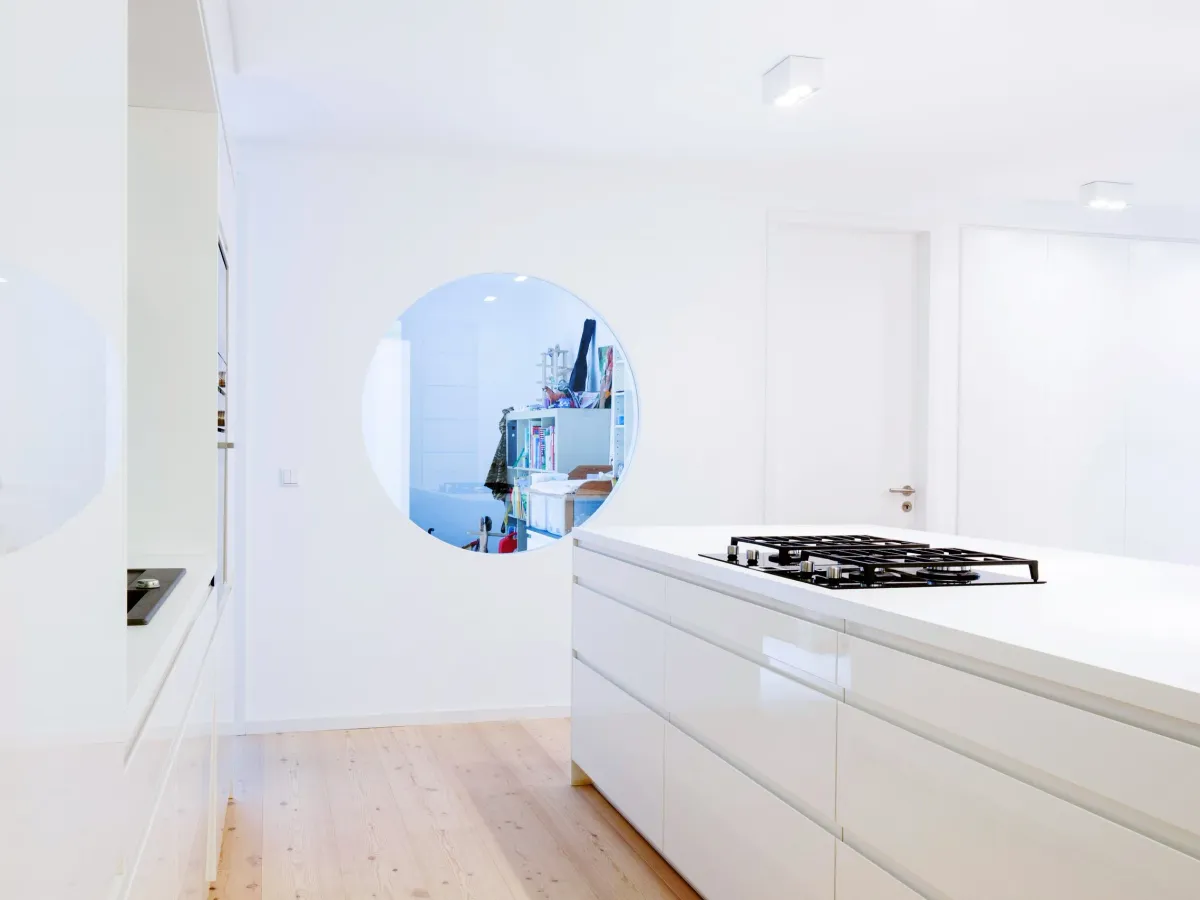 Kochinsel mit Gaskochfeld und rundem Fensterausschnitt zum Kinderzimmer
