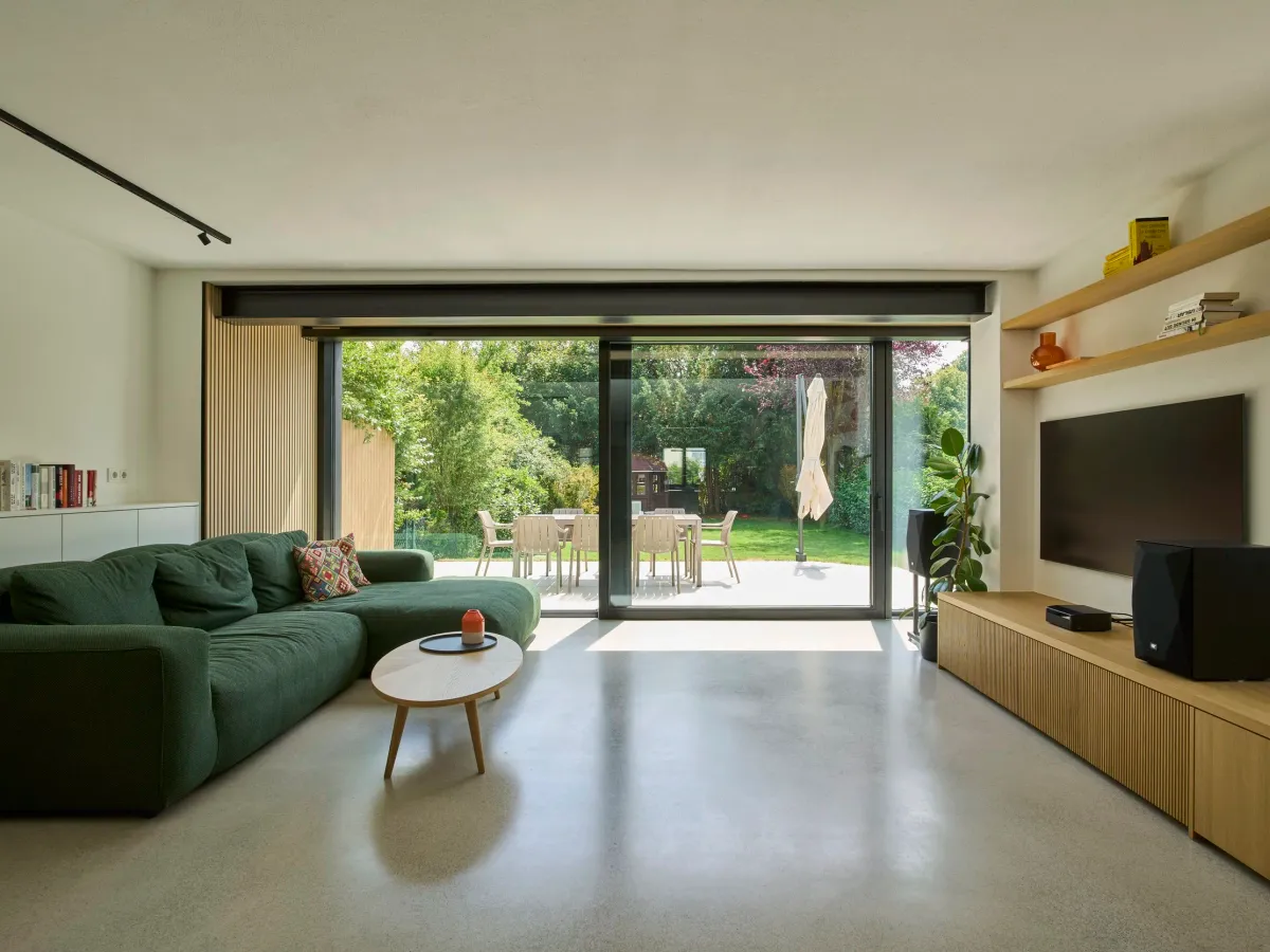 Wohnzimmer mit Sofa und offener Terrassenfront zum Garten