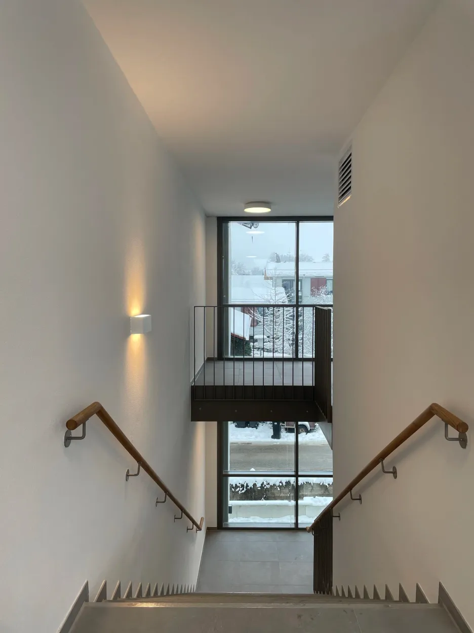Treppenhaus mit Holzhandlauf und Blick zum Balkon