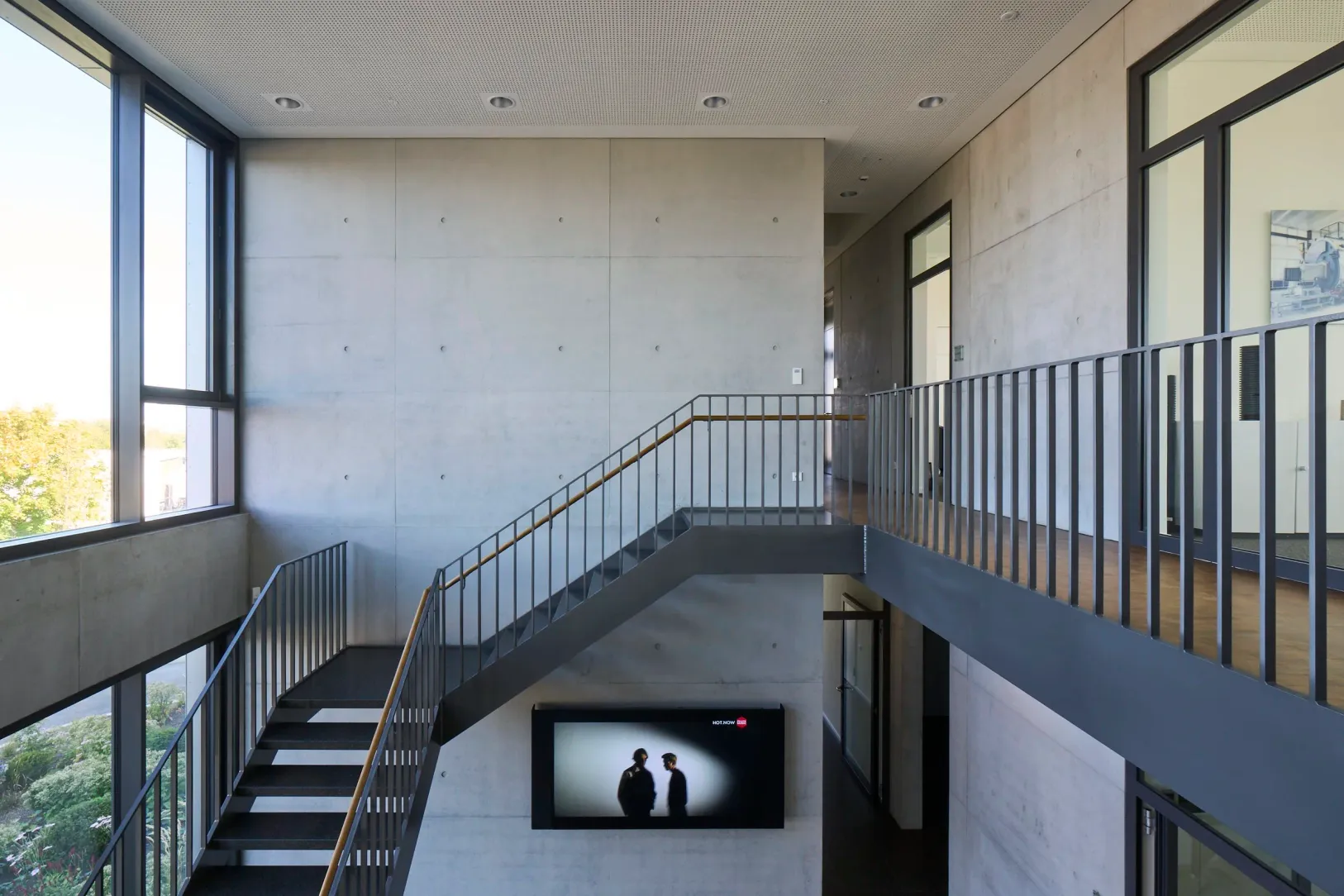 Galerie im Obergeschoss mit Blick auf Treppe und Sichtbetonwand