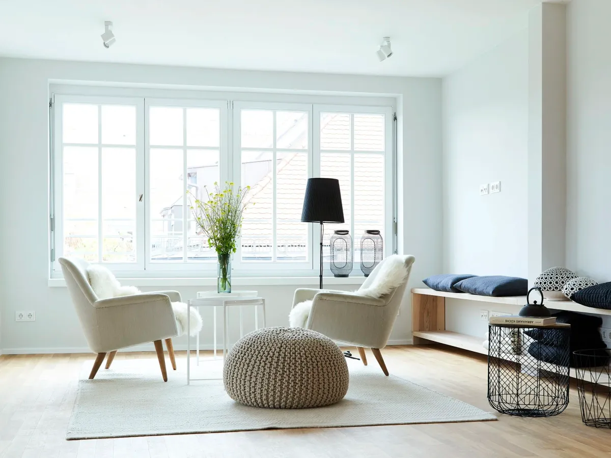 Wohnzimmer mit Altbaufenster, Sesseln und Stehlampe