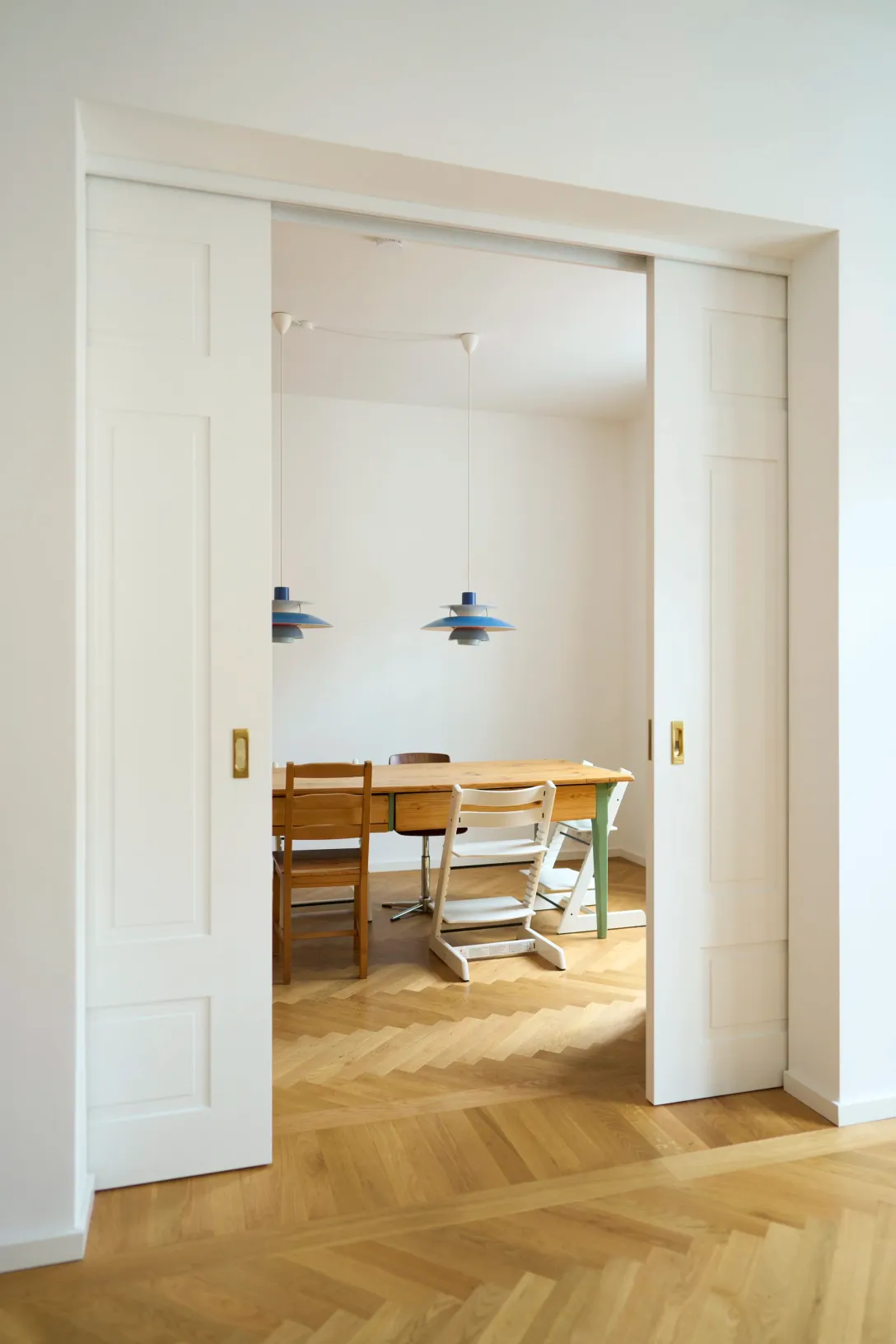 Esszimmer mit blauen Pendelleuchten über dem Holztisch