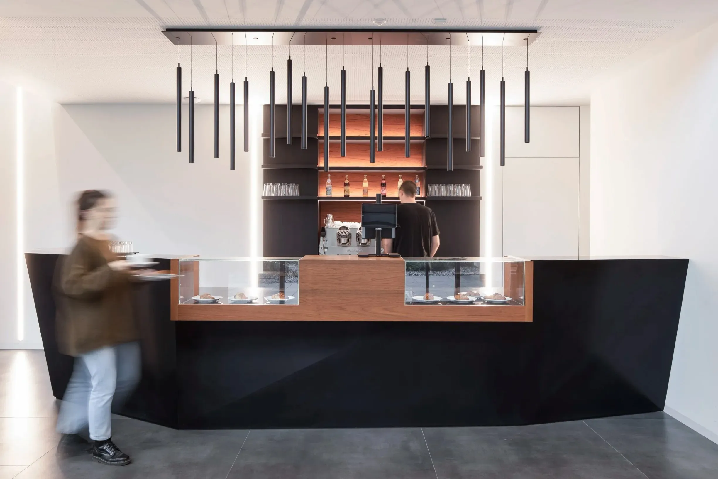 Kaffeebar mit Gebäckvitrine und Hängeleuchten-Reihe