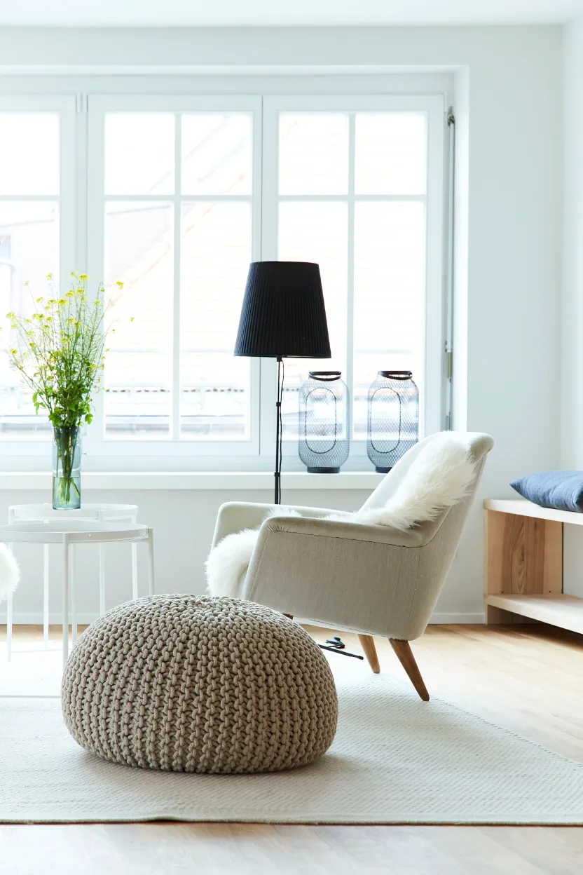 Sessel mit Fell und Strickpouf vor dem Altbaufenster